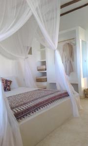 a bedroom with a bed with white drapes at Shira house in Watamu