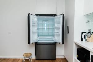 an empty refrigerator with its door open in a kitchen at The Nest Beach Getaway in Torquay