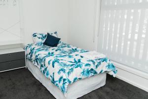 een slaapkamer met een bed met een blauwe en witte deken bij The Nest Beach Getaway in Torquay