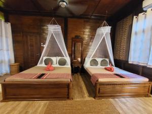two beds sitting in a room with windows at Ombak Dive Resort Perhentian Island in Perhentian Islands