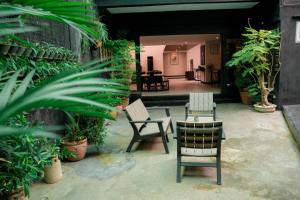 un patio avec des chaises, des tables et des plantes dans l'établissement Tropical Poolhouse QC, à Manille