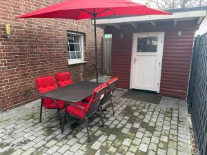 einen Tisch und Stühle mit einem roten Regenschirm auf einer Terrasse in der Unterkunft Ferienwohnung Grefenhof in Meerbusch