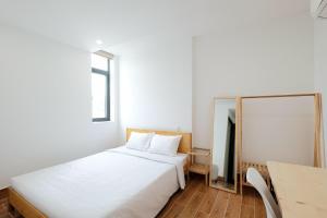 a bedroom with a white bed and a table at Fisherman Homestay PQ - by BAY LUXURY in Phu Quoc