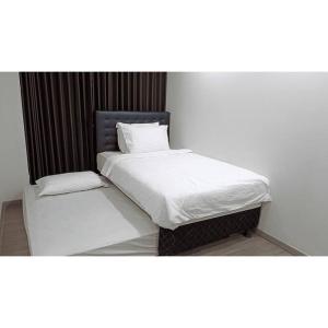 Bett mit weißer Bettwäsche und Kissen in einem Zimmer in der Unterkunft Cityscape @ Caspian in Surabaya