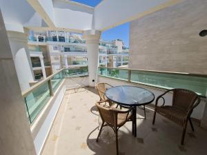 a balcony with a glass table and two chairs at Palmore Top Luxury Resort First line of the Seaside in Eilat