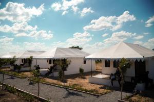 Une rangée de tentes blanches avec des arbres devant dans l'établissement Jawai Empire Resort by Premier Hotels, à Pāli