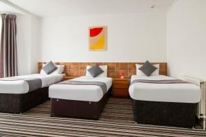 una habitación de hotel con 3 camas. en OYO The Contractor Hotel, en South Bank