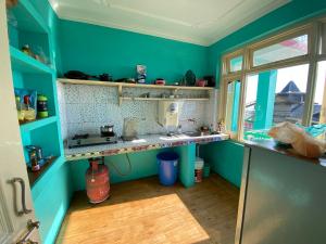 a blue kitchen with a sink and a window at Jagatram Niwas in Dharamshala
