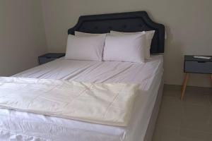 a large bed with white sheets and pillows at GreenLake Vista in Surabaya