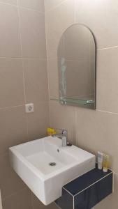 La salle de bains est pourvue d'un lavabo blanc et d'un miroir. dans l'établissement GreenLake Vista, à Surabaya