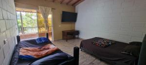 a room with two beds and a television on the wall at Cabaña rodeada de naturaleza in Cocorná