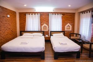 two beds in a room with a brick wall at Sweet Home Bhaktapur in Bhaktapur