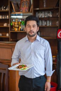 a man holding a plate of food in a restaurant at Sweet Home Bhaktapur in Bhaktapur