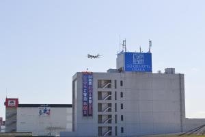 an airplane is flying over a building at グッドホテル大阪 in Toyonaka