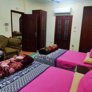 two beds sitting in a room with pink sheets at Amazing Mountain View-Near City Center in Luxor