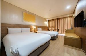 Habitación de hotel con 2 camas y TV de pantalla plana. en S Hotel en Jeju