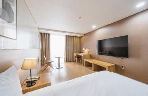 um quarto de hotel com uma cama e uma televisão de ecrã plano em S Hotel em Jeju