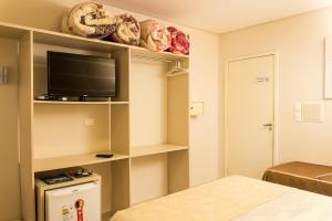 a room with a bed and a tv on a shelf at Pousada Cataratas in Foz do Iguaçu