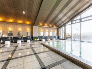 an indoor swimming pool with chairs and a large window at Tabist Healthy Pal Akagi in Shibukawa +48 photos