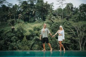 a couple holding hands while standing on top of a pool at Horison Ume Suites & Villas in Ubud