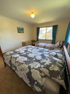 um quarto com uma cama com um edredão floral em Narooma/Dalmeny Fishermens Lodge em Dalmeny