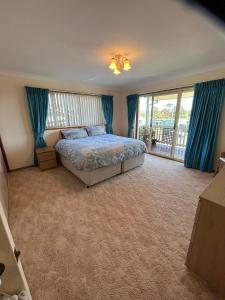 um quarto com uma cama com cortinas azuis e uma varanda em Narooma/Dalmeny Fishermens Lodge em Dalmeny