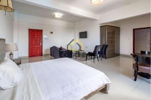 a bedroom with a white bed and a desk and chairs at Hotel Kilimanjaro - Luanda Angola in Luanda