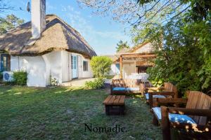 a cottage with a thatched roof and a table and benches at Casa en Punta del Este in Punta del Este