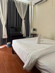 een slaapkamer met een groot wit bed en een bureau bij Champa Inn Hotel in Vang Vieng