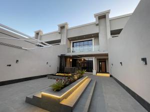 شاليهات راف في خميس مشيط: مبنى أبيض كبير مع مقعد في ساحة الفناء