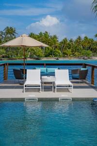 - une terrasse avec des chaises et un parasol à côté de l'eau dans l'établissement Motu Fara Private Island, à Avatoru