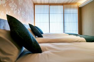 a room with three beds with green pillows on them at Kikokutei Bekkan in Kyoto
