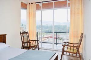 1 dormitorio con 1 cama, 2 sillas y una ventana grande en Channa villa, en Nuwara Eliya