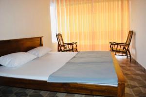 1 dormitorio con 1 cama grande y 2 sillas en Channa villa, en Nuwara Eliya