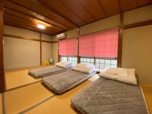 two beds in a room with a window at Naoshima J-House in Naoshima