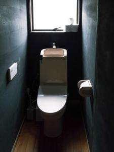 a bathroom with a white toilet with a window at まちごとホテルLOOP 小林 in Makata