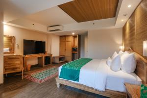 a hotel room with a bed and a flat screen tv at Horison Ume Suites & Villas in Ubud