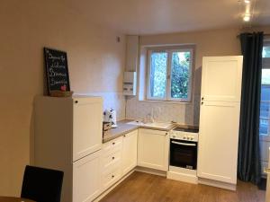 a kitchen with white cabinets and a white refrigerator at Appartement 1 chambre terrasse 200m de la plage et GR34 in Saint-Lunaire