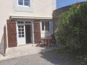 a house with a wooden door and a table outside at Appartement 1 chambre terrasse 200m de la plage et GR34 in Saint-Lunaire +4 photos