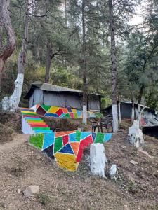 a colorful encampment with a tent in the woods at Jungle Stays in Chail