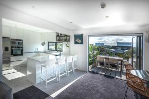 a kitchen with white cabinets and a table and chairs at Orewa Beachcomber in Orewa