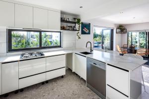 a kitchen with white cabinets and a large window at Orewa Beachcomber in Orewa