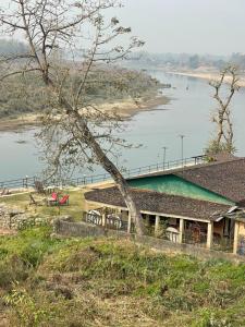 a building on a hill next to a lake at Chitwan Riverside Resort in Sauraha