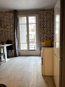 een woonkamer met een koelkast en een raam bij 5min from Paris / Cosy Appartment in Levallois-Perret