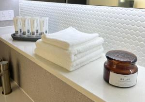 a bathroom counter with towels and a jar of honey at Harbour Towers, Newcastle's Luxe Apartment Stays in Newcastle