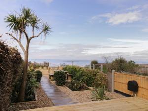 a garden with a palm tree and a wooden walkway at Coastguards View in Herne Bay
