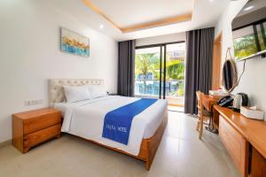 a bedroom with a bed and a desk and a window at Hana Hotel Sonasea Night Market Phu Quoc in Phú Quốc