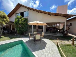 een huis met een zwembad en een tafel met een parasol bij Estância Zuliani in Guriri