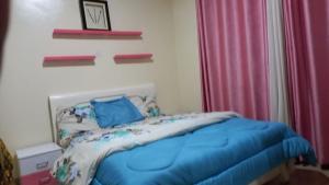 a bedroom with a blue bed and a pink curtain at Tommy's Budget Rooms in Kigali