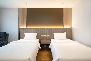 two beds in a room with white sheets at Crystal Srivaree Suvarnabhumi Hotel in Ban Khlong Bang Krathiam